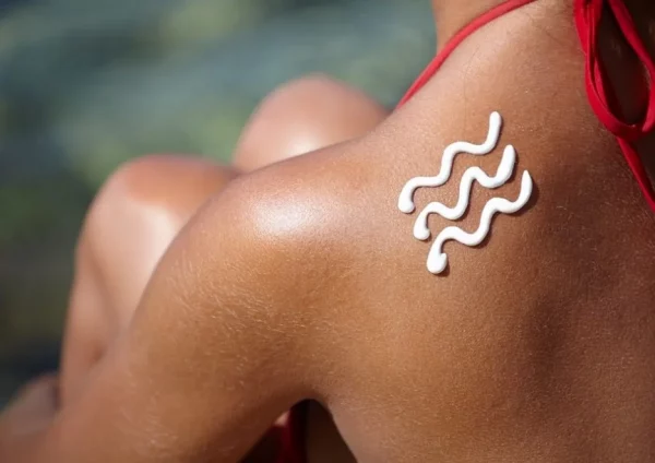 vagues dessinées sur l'épaule d'une jeune femme avec de la crème solaire