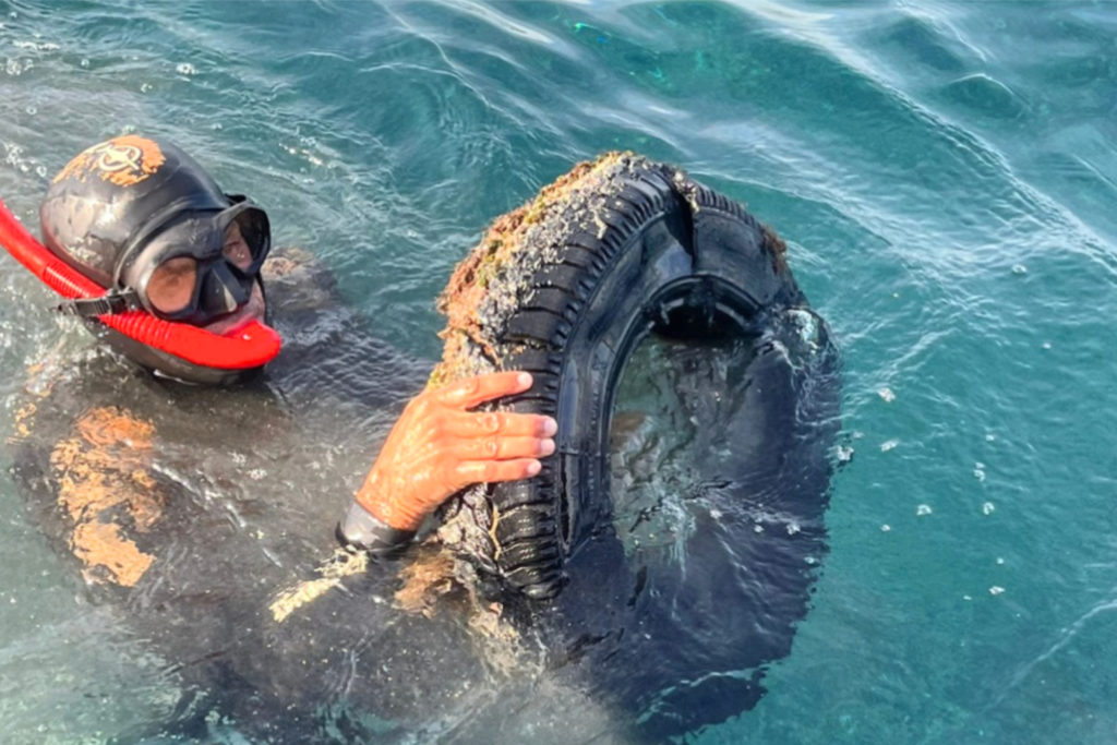 Plongeur retirant un pneu de la mer