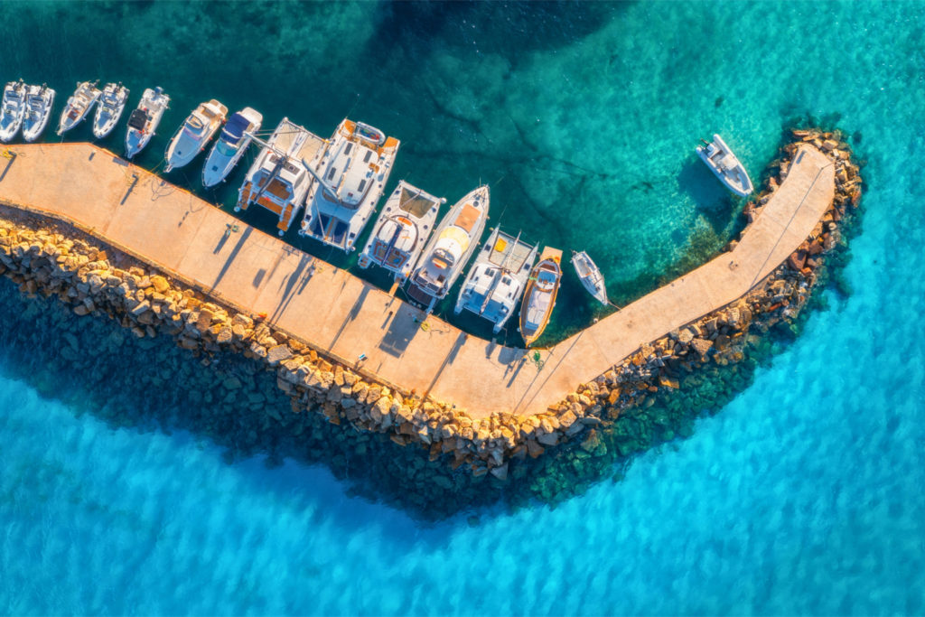 Vue aérienne de bateaux à moteur et catamarans amarrés dans une marina aux eaux turquoise